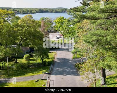 A drone view of Lake Attitash surrounded by greenery on a sunny day in Massachusetts Stock Photo