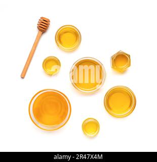 Creative composition of honey jars and wooden dipper on isolation top view. Honey in a glass bowl of different sizes and a stick for honey on a white Stock Photo