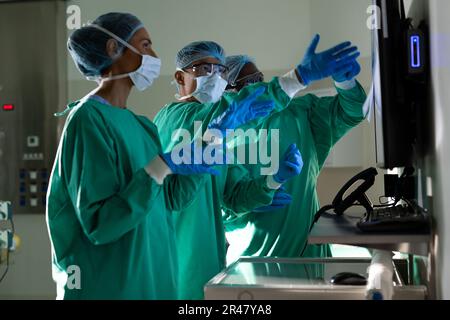 Diverse male and female surgeons discussing x-rays in operating theatre before surgery Stock Photo