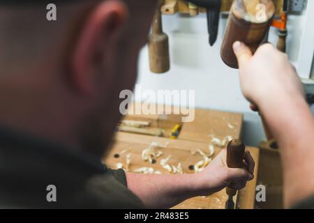 Carpenter using a chisel and a hammer to carve wood on a carpentry workbench. High quality photo Stock Photo