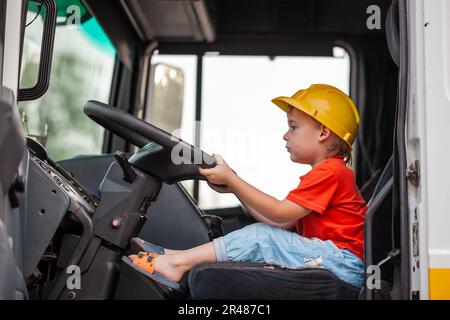 Little boy driving tractor. Son helps father to repair tractor. Involve child in work Stock Photo