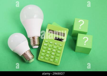 Light bulb, Green calculator, question mark on green background. Concept competition for Green Energy market Stock Photo
