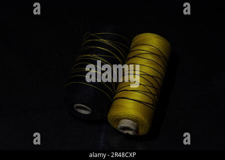 A closeup of two rolls of sewing threads on a black background Stock Photo