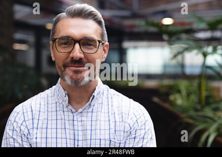 Portrait of happy caucasian businessman looking at camera and smiling at office, unaltered Stock Photo
