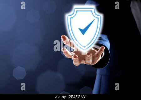 Anti-fraud security system. Man with illustration of checkmark in shield on dark background, closeup. Space for text Stock Photo