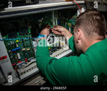 230405-N-NX635-1106 (April 5, 2023) US Navy Aviation Support Equipment Technician 2nd Class Andrew Dickinson, from Marthasville, Mo., troubleshoots a static frequency converter in the hangar bay aboard the aircraft carrier USS Nimitz (CVN 68). The Nimitz Carrier Strike Group is conducting a bilateral maritime exercise with the Republic of Korea Navy in the U.S. 7th Fleet area of operations. 7th Fleet is the U.S. Navy’s largest forward-deployed numbers fleet, and routinely interacts and operates with Allies and partners in preserving a free and open Indo-Pacific region. Stock Photo