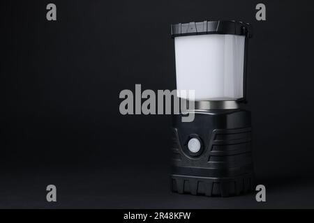Camping lantern on black background, space for text. Military training equipment Stock Photo