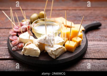 Toothpick appetizers. Pieces of cheese, sausage and honey on wooden table, closeup Stock Photo