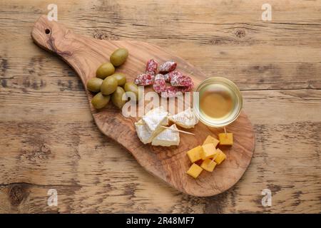 Toothpick appetizers. Pieces of sausage, cheese and honey on wooden table, top view Stock Photo