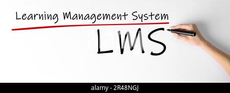 Woman writing abbreviation LMS below underlined Learning Management System text on whiteboard, closeup. Banner design Stock Photo
