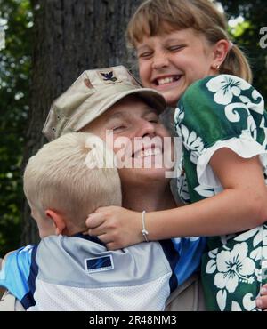 US Navy Utilitiesman 1st Class gets a big hug from his children at the main gate to Naval Station, Great Lakes Stock Photo