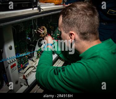 230405-N-NX635-1112 (April 5, 2023) US Navy Aviation Support Equipment Technician 2nd Class Andrew Dickinson, from Marthasville, Mo., troubleshoots a static frequency converter in the hangar bay aboard the aircraft carrier USS Nimitz (CVN 68). The Nimitz Carrier Strike Group is conducting a bilateral maritime exercise with the Republic of Korea Navy in the U.S. 7th Fleet area of operations. 7th Fleet is the U.S. Navy’s largest forward-deployed numbers fleet, and routinely interacts and operates with Allies and partners in preserving a free and open Indo-Pacific region. Stock Photo