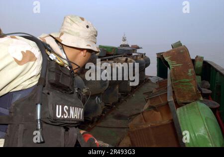 US Navy A Vessel, Board, Search and Seizure (VBSS) team member inspects camouflaged mines hidden inside oil barrels on the deck of an Iraqi shipping barge Stock Photo