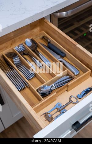 A wooden drawer containing various types of kitchen utensils Stock Photo