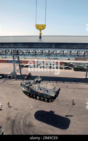 US Navy Personnel assigned to the Navy's cargo handling and port group (NAVCHAPGRU) maintains a steady hold on a tending line attached to an Amphibious Assault Vehicle (AAV) as it is lifted by crane into the Stock Photo