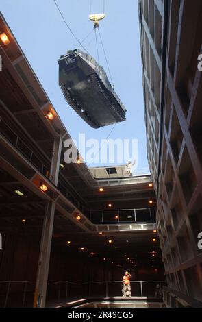 US Navy Personnel assigned to the Navy's cargo handling and port group (NAVCHAPGRU) maintains a steady hold on a tending line attached to an Amphibious Assault Vehicle (AAV) as it is lifted by crane into the Stock Photo