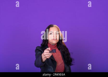 Woman showing a credit card on purple background. Shopping concept. Studio shot. Stock Photo