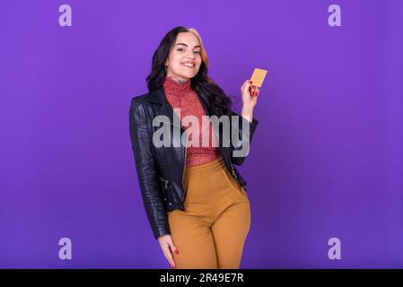 Woman showing a credit card on purple background. Shopping concept. Studio shot. Stock Photo