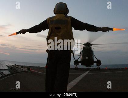 US Navy Boatswain's Mate 1st Class provides the hover signal to the pilot of a helicopter Stock Photo
