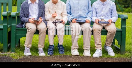 A diverse group of college-aged students enjoying a sunny day in the park using their gadgets Stock Photo