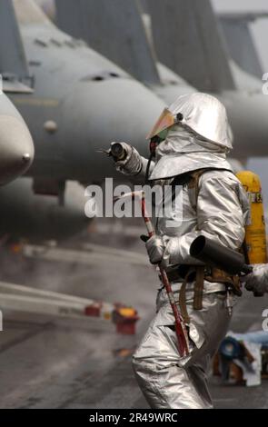 US Navy A crash and salvage crew member moves-in to overhaul a simulated aircraft fire while participating in flight deck drills aboard USS Harry S. Truman (CVN 75) Stock Photo