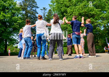 A diverse group of smiling people, celebrating the sunshine and dancing together joyfully in a circle on a beautiful sunny day Stock Photo