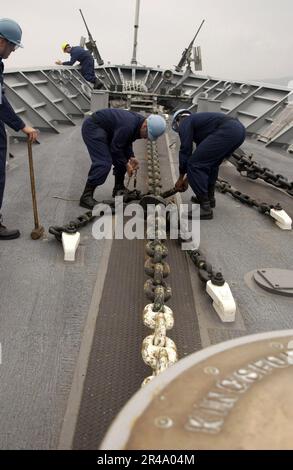 US Navy Deck Department Sailors aboard the guided missile cruiser USS Cowpens (CG 63) remove the chain stoppers Stock Photo