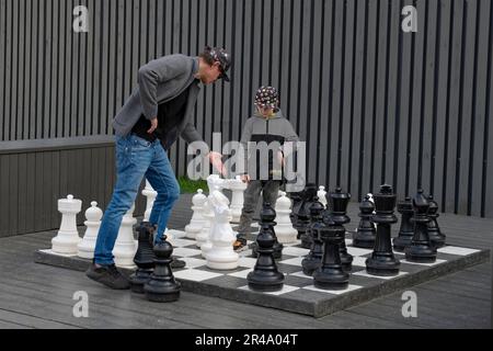 SAINT PETERSBURG, RUSSIA - MAY 14, 2023: Father and son play floor chess on the territory of the cultural and entertainment complex New Holland Stock Photo