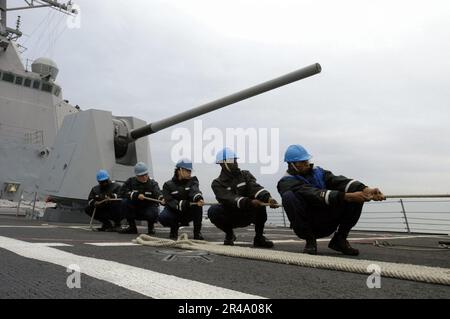 US Navy Deck department personnel assigned to the guided missile destroyer USS Shoup (DDG 86) tend a line Stock Photo