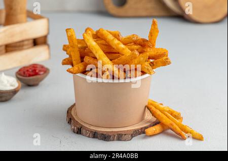A bowl filled with freshly cooked French fries topped with ketchup and sour cream Stock Photo
