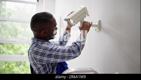 Close-up Of Technician Adjusting CCTV Camera On Wall Stock Photo