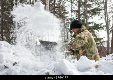 U.S. Army Staff Sgt. Quinnzale Tisdale, a paratrooper assigned to Headquarters and Headquarters Company, 2nd Infantry Brigade Combat Team (Airborne), 11th Airborne Division, clears the area of snow for tent construction at Husky Drop Zone in Yukon Training Area, Ft. Wainwright, Alaska, March 29, 2023, during Joint Pacific Multinational Readiness Center-Alaska 23-02. JPMRC-AK 23-02 helps Soldiers and leaders develop and refine the tactics, techniques, and procedures necessary to successfully operate in remote and extreme Arctic winter conditions and overcome environmental and military challenge Stock Photo