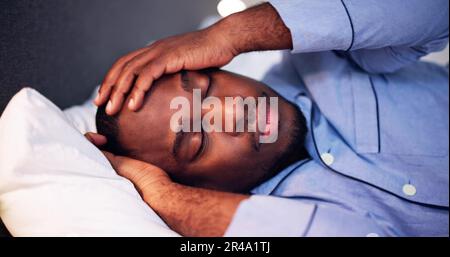 Young African Man Suffering From Fever Lying On Bed Stock Photo