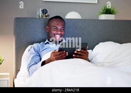 Man Lying On Bed Looking At Illuminated Digital Tablet Stock Photo
