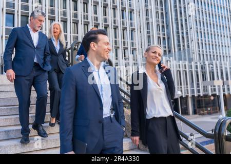 A group of business professionals are walking down a staircase while engaged in a conversation Stock Photo