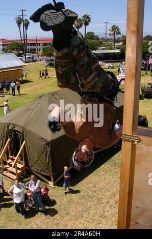 US Navy Utilitiesman 1st Class displays different repelling techniques while the crowd watches from below at Seabee days Stock Photo