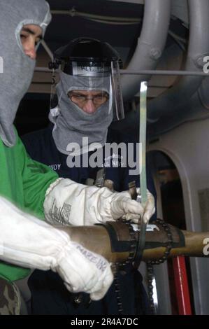 US Navy Sailors assigned to Damage Control Repair Locker One Alpha (1A) practice pipe-patching techniques during a General Quarters Stock Photo