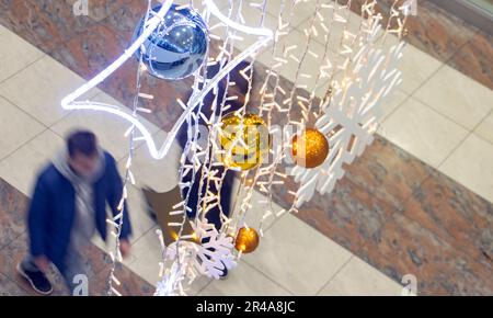 People walk under the Christmas decorations hanging in the airport hall Stock Photo