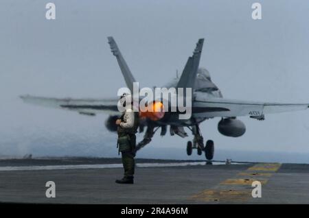 US Navy A flight deck crew member looks on as an F-A-18C Hornet is catapulted from the flight deck aboard USS John C. Stennis (CVN 74) Stock Photo