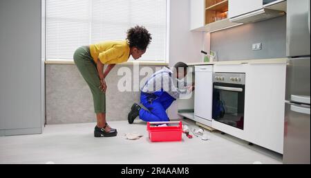 Plumber Cleaning Drain And Pipe In Kitchen Stock Photo