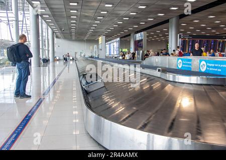 BANGKOK, THAILAND, JAN 20 2023, Passengers are waiting for their luggage on the conveyor in the arrivals hall of the airport Stock Photo