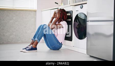 Frustrated Young Woman Sitting On Kitchen Floor Stock Photo
