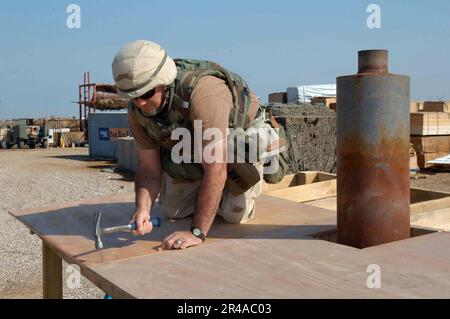 US Navy Utilitiesman 1st Class assigned to Naval Mobile Construction Battalion Two Three (NMCB-23), nails roof sheathing to a hut protecting an electric generator Stock Photo