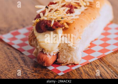A delicious and juicy hot dog served on a soft and lightly toasted bun on a wooden table. Stock Photo