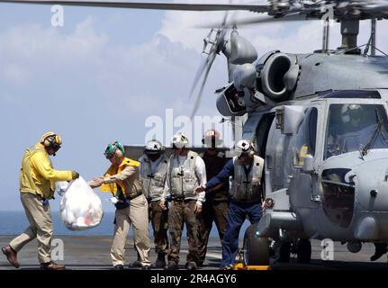 US Navy Crew members aboard USS Abraham Lincoln (CVN 72), load bags of toys onto an HH-60H Seahawk helicopter Stock Photo