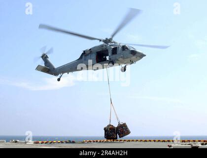 US Navy An MH-60S Knighthawk helicopter lifts off with a cargo net of relief supplies, from the flight deck of the amphibious assault ship USS Bonhomme Richard (LHD 6) Stock Photo