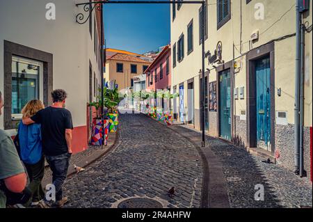 A couple walking side by side down a narrow alleyway in Madeira. Stock Photo