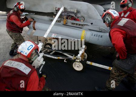 US Navy U.S. Marines Corps Ordnancemen hoist an AGM-65 Maverick laser-guided missile to a weapons pylon under the wing of one of their squadron's F-A-18A- Hornets Stock Photo