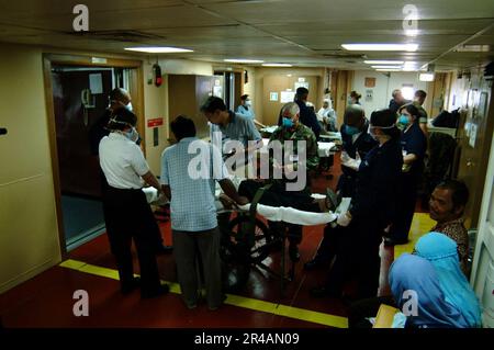 US Navy U.S. Navy Hospital Corpsmen, assigned to Navy Environmental and Preventive Medicine Unit Six (NEPMU-6), and an Indonesian interpreter, assess patients evacuated from Banda Ache, Sumatra Indonesia, Stock Photo