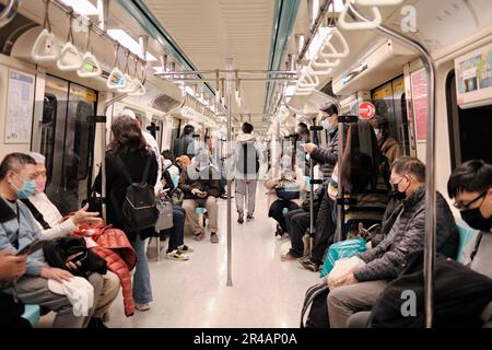 A diverse group of adults are packed together in a public transportation vehicle, all using their mobile devices in an urban setting Stock Photo